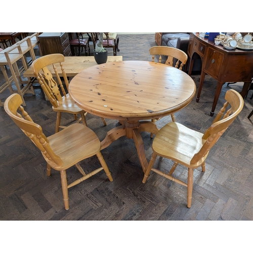 A varnished pine circular single pedestal kitchen table and ...