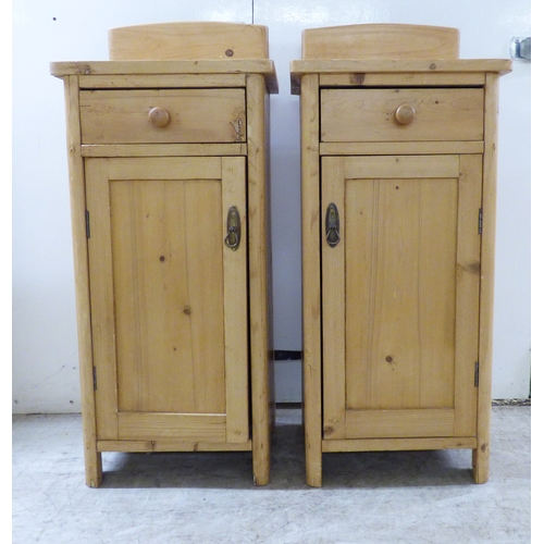 A pair of early 20thC pine bedside cabinets, each with a doo...