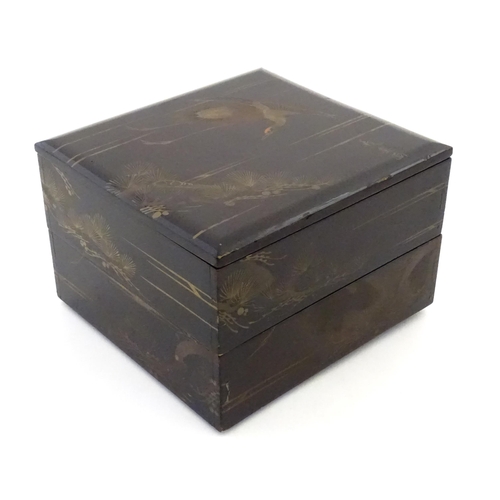 A Japanese black lacquered two tier box with crane and pine ...