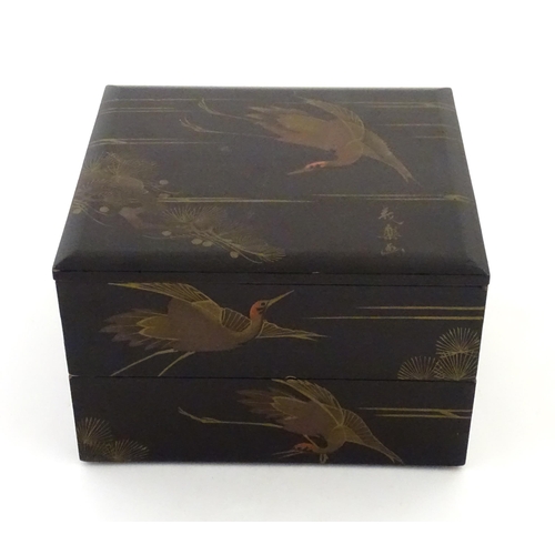A Japanese black lacquered two tier box decorated with crane...